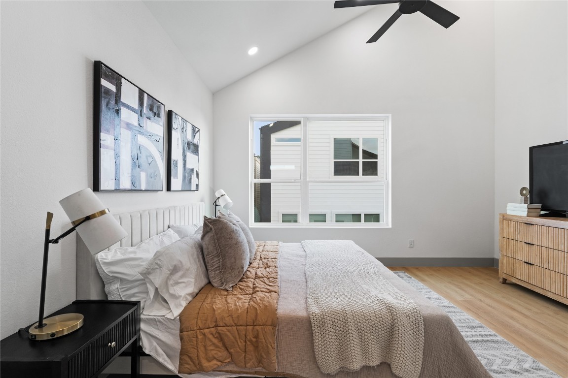 2950 Pitzlin Street Houston, TX 77023 - Photo 21 of 37 Wake up beneath soaring vaulted ceilings and unwind in the glow of natural light streaming through oversized windows. This serene primary bedroom blends modern scale with cozy texture, creating a calming space to start and end each day.