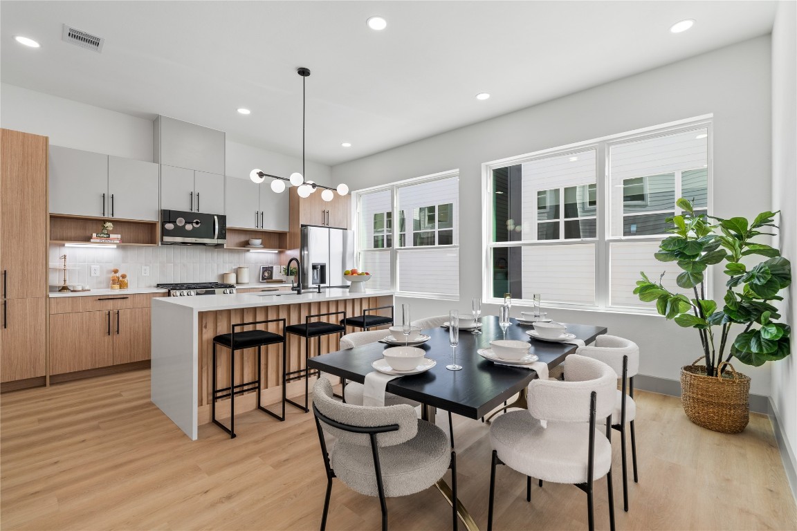 2950 Pitzlin Street Houston, TX 77023 - Photo 7 of 37 Thoughtfully designed with clean lines and elevated finishes, this kitchen-dining combo features custom flat-panel cabinetry, soft-close drawers, quartz countertops, and a spacious island with waterfall detail—bathed in natural light from oversized energy-efficient windows.