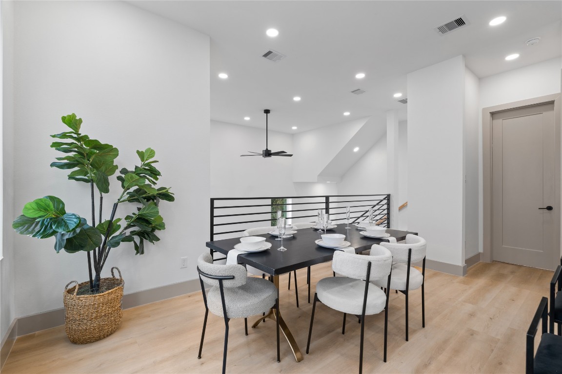 2950 Pitzlin Street Houston, TX 77023 - Photo 8 of 37 Overlooking the dramatic two-story living room, this open dining area features modern railing details, recessed lighting, and wide-plank SPC flooring—blending form and function in an architecturally distinct layout.