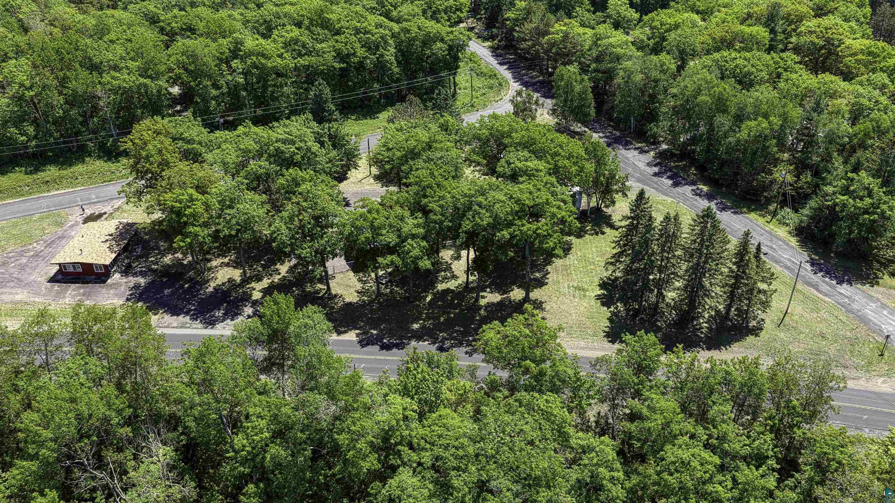 66075 Rooster Road Iron River, WI 54847 - Photo 6 of 52 Expansive wooded acreage featuring a single-story structure with a light-colored roof, surrounded by mature deciduous and coniferous trees