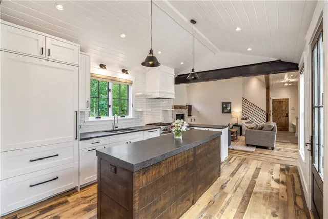 a large kitchen with kitchen island a large window a sink and stainless steel appliances