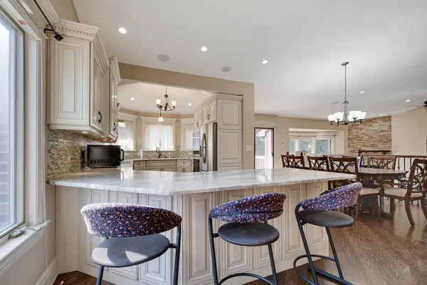 a kitchen with stainless steel appliances granite countertop a stove a sink refrigerator and a dining table with wooden floor