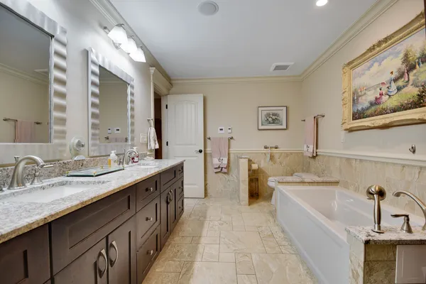 a spacious bathroom with a double vanity sink mirror and bathtub