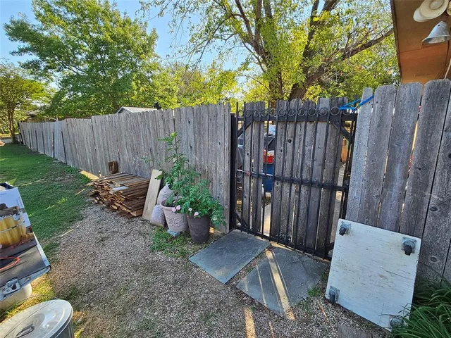 a view of a backyard with wooden fence and a large tree