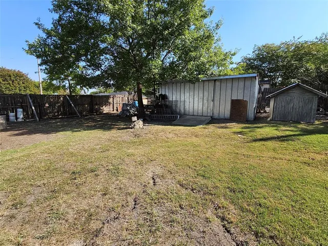 a view of a backyard with table and chairs and a large tree