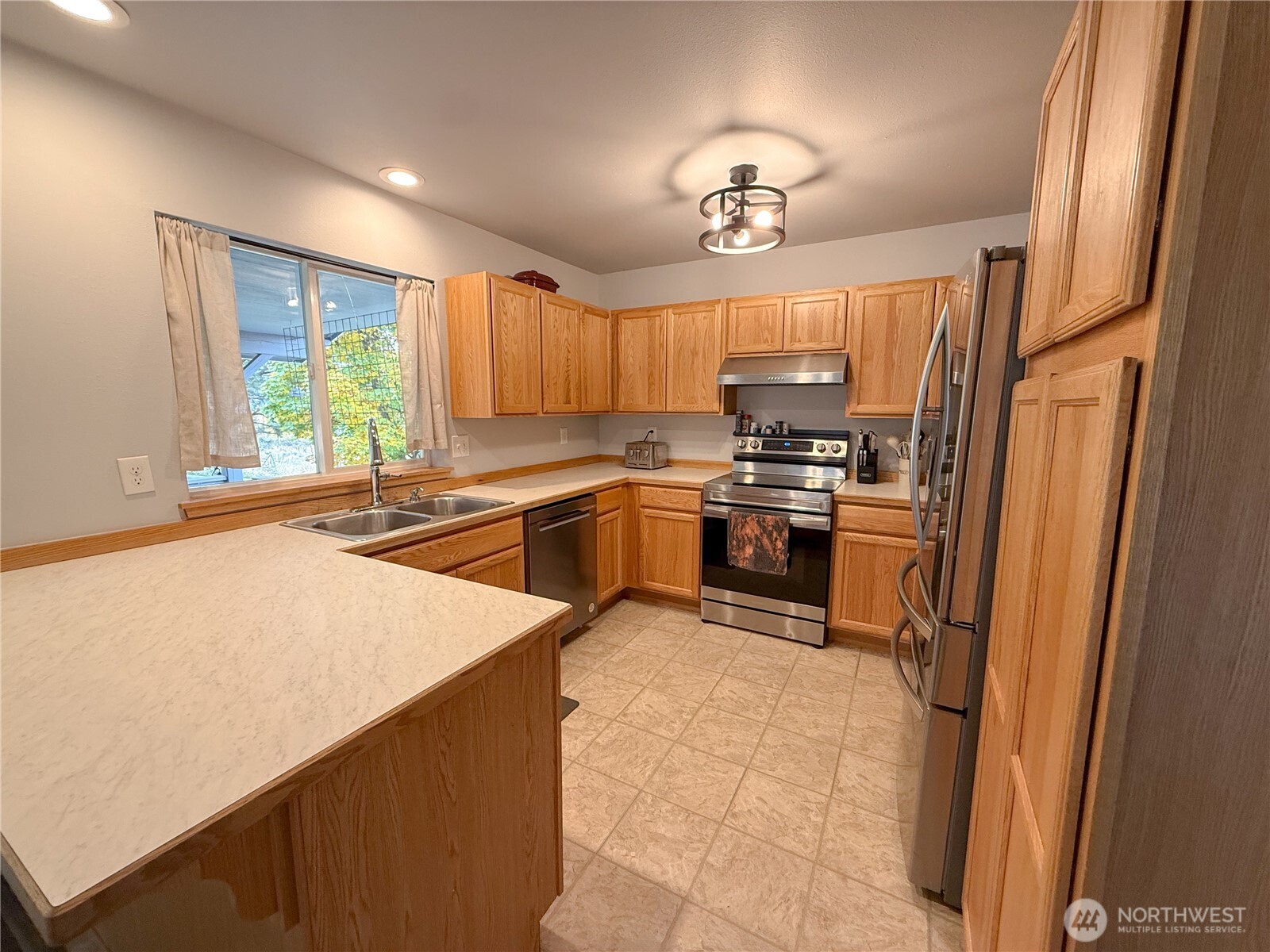 40 Trail Ridge Drive Omak, WA 98841 - Photo 9 of 36 a kitchen with wooden cabinets a sink a stove and a refrigerator