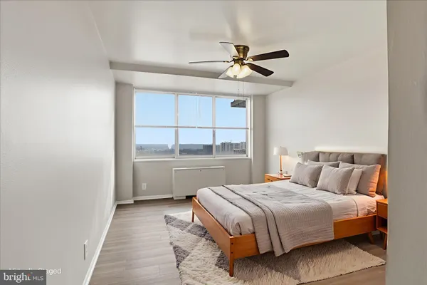 an empty room with wooden floor fan and windows