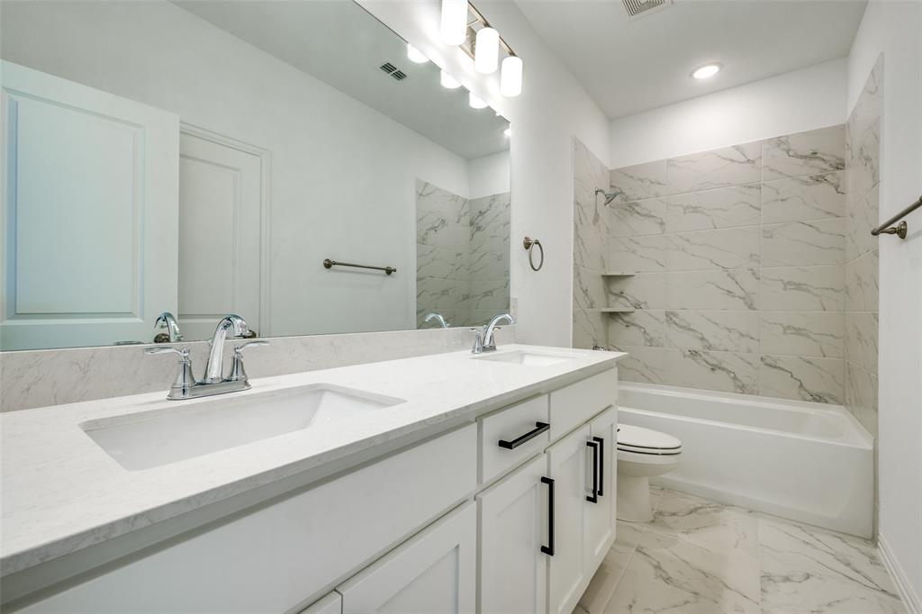 7336 Panicum Drive Frisco, TX 75033 - Photo 15 of 25 a bathroom with a double vanity sink mirror toilet and bathtub