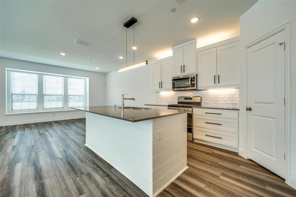 7336 Panicum Drive Frisco, TX 75033 - Photo 7 of 25 a kitchen with stainless steel appliances granite countertop a stove a sink and a refrigerator