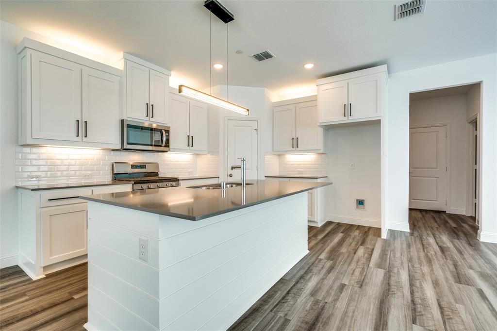 7336 Panicum Drive Frisco, TX 75033 - Photo 8 of 25 a kitchen with kitchen island granite countertop a sink appliances cabinets and a counter top space