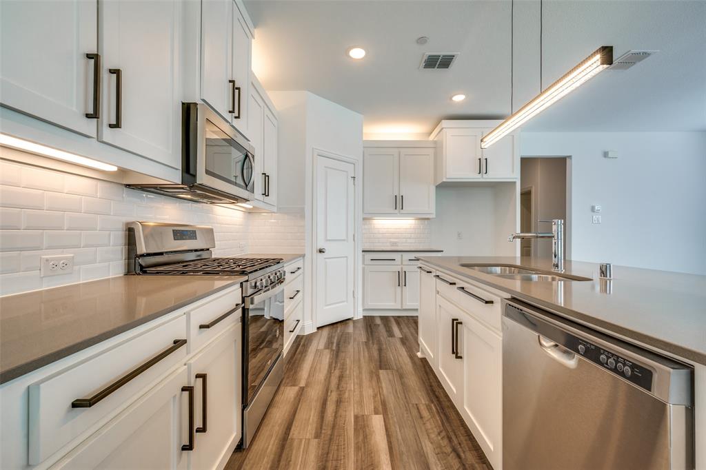 7336 Panicum Drive Frisco, TX 75033 - Photo 9 of 25 a kitchen with stainless steel appliances a sink stove and cabinets