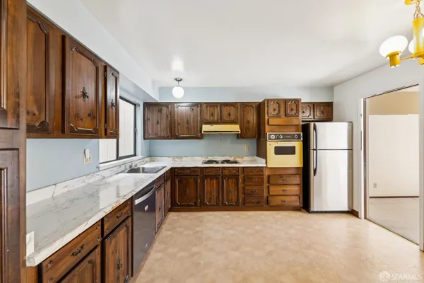 a kitchen with stainless steel appliances granite countertop a refrigerator a stove and a sink with wooden cabinets