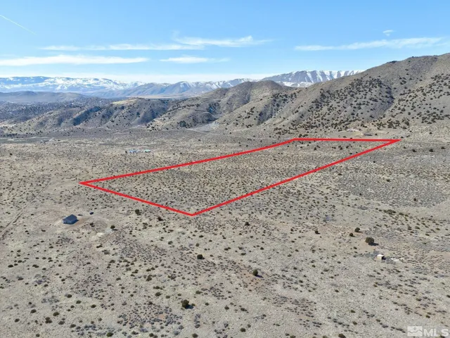 a view of a dry field with mountains in the background