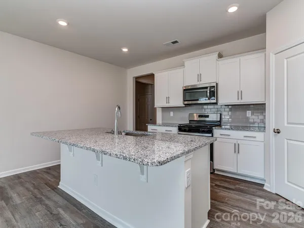 a kitchen with stainless steel appliances granite countertop a sink stove and microwave