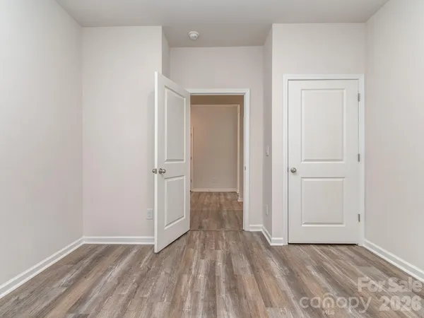 a view of an empty room with wooden floor and closet