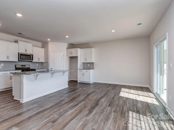 a view of kitchen with granite countertop stainless steel appliances refrigerator sink and microwave