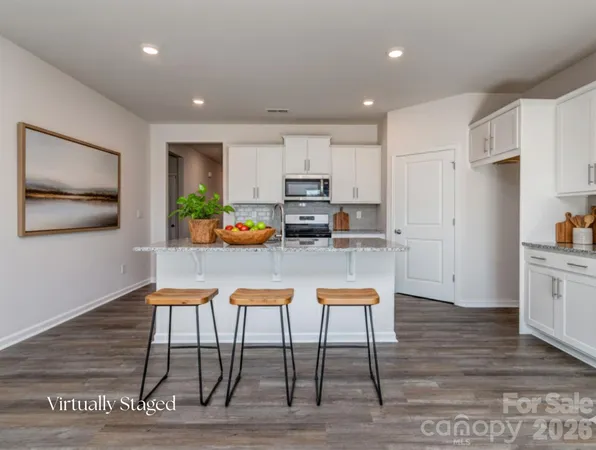 a kitchen with stainless steel appliances granite countertop a stove a refrigerator a kitchen island with a stove and white cabinets