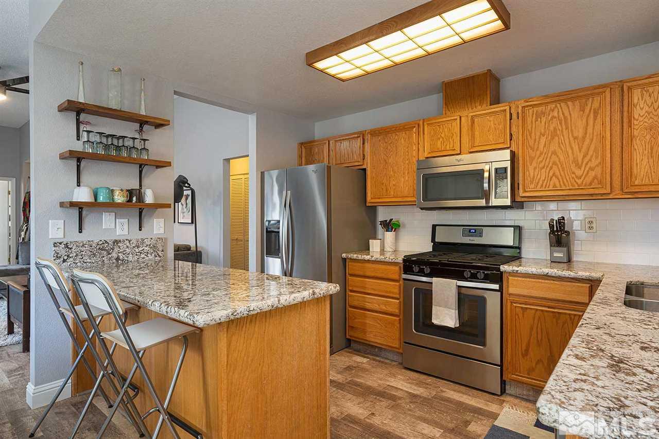 1065 Backer Way Reno, NV 89523 - Photo 6 of 25 a kitchen with stainless steel appliances granite countertop a stove top oven a sink dishwasher a dining table and chairs with wooden floor