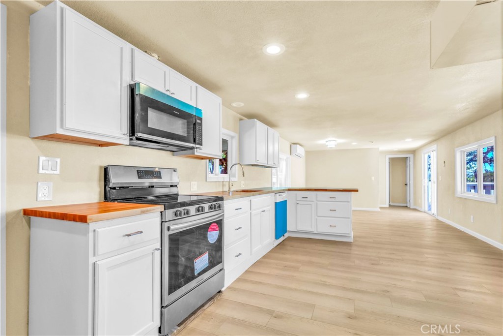 15905 Kugelman Street Lower Lake, CA 95457 - Photo 36 of 75 a kitchen with stainless steel appliances a stove top oven a sink a refrigerator white cabinets and wooden floor