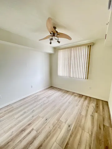 an empty room with wooden floor fan and windows