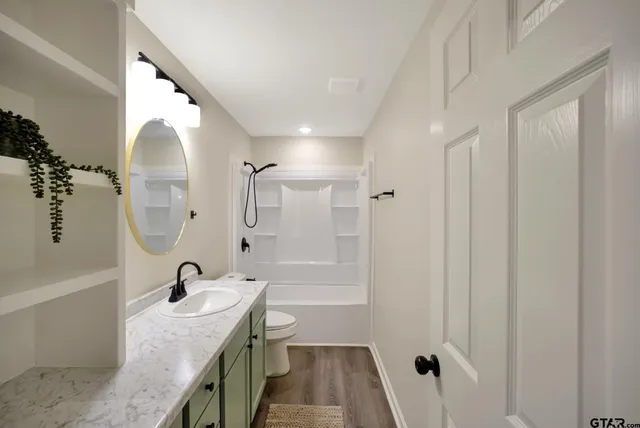 a bathroom with a granite countertop sink a toilet and shower