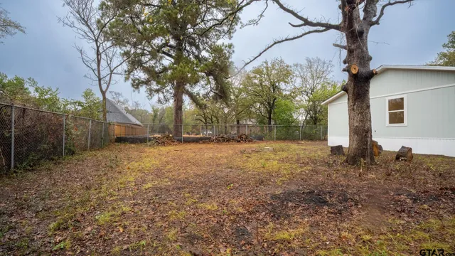 a backyard of a house with large trees and wooden fence