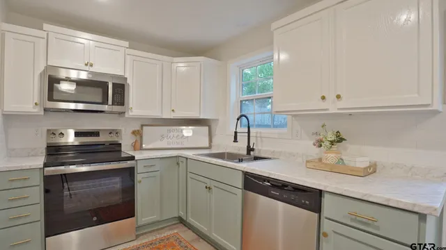 a kitchen with cabinets stainless steel appliances a sink and a microwave
