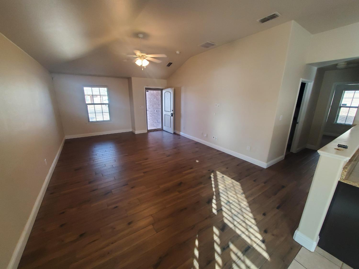 5603 110th Street Lubbock, TX 79424 - Photo 2 of 12 a view of an empty room with wooden floor and a window