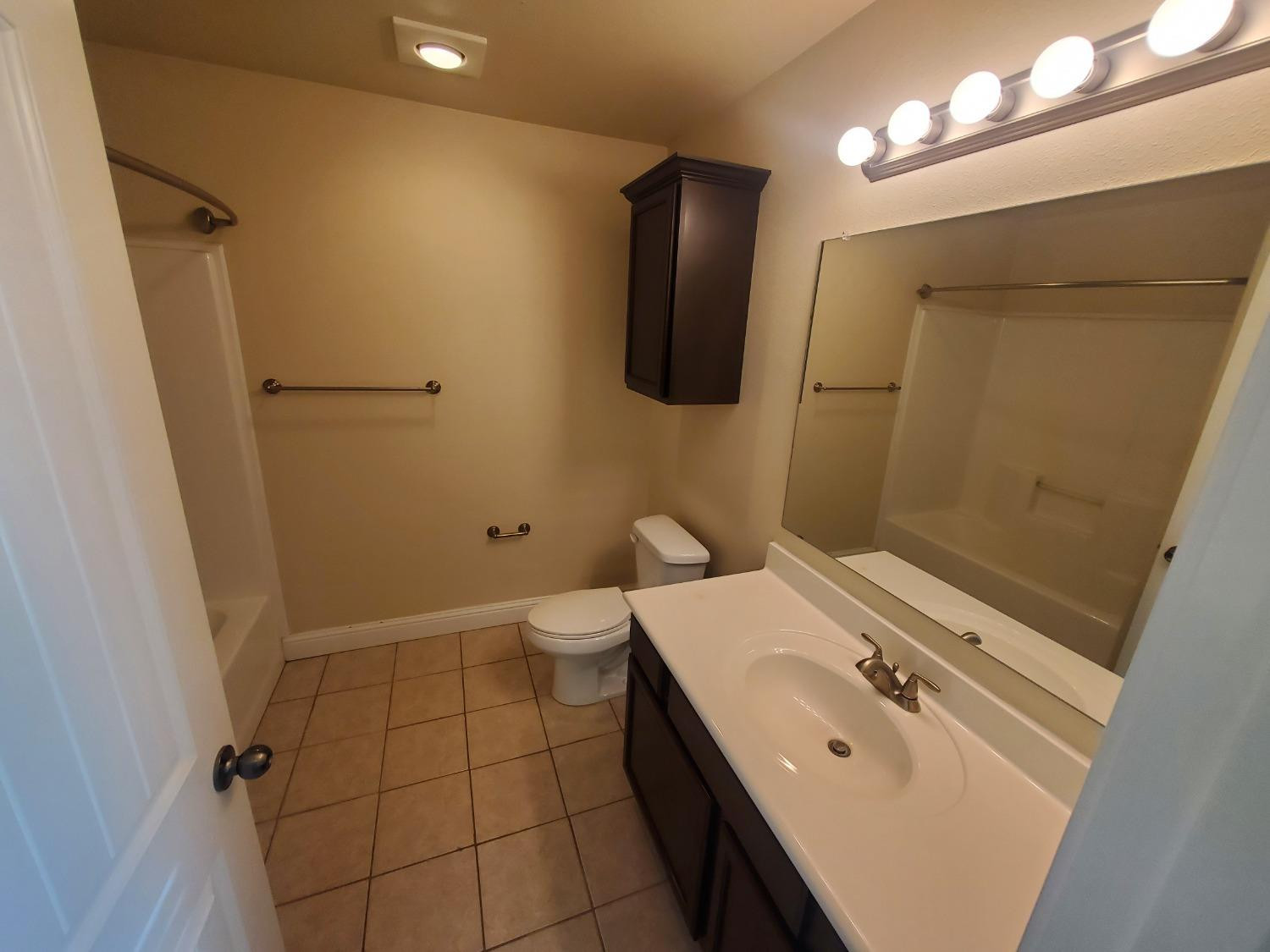 5603 110th Street Lubbock, TX 79424 - Photo 6 of 12 a bathroom with a sink a toilet and mirror