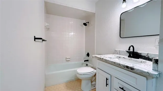 a bathroom with a granite countertop sink a toilet and a mirror