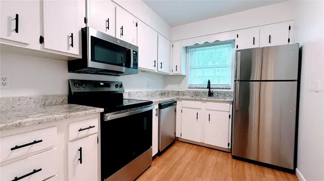 a kitchen with a sink a refrigerator a microwave and cabinets