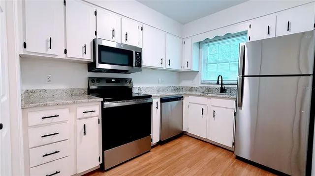 a kitchen with white cabinets and stainless steel appliances