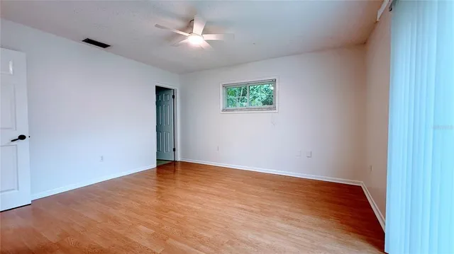 an empty room with wooden floor and fan
