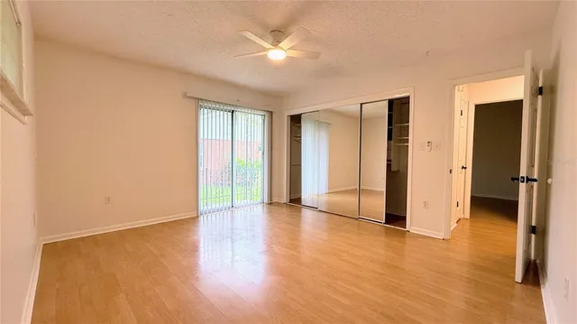 an empty room with wooden floor and a ceiling fan