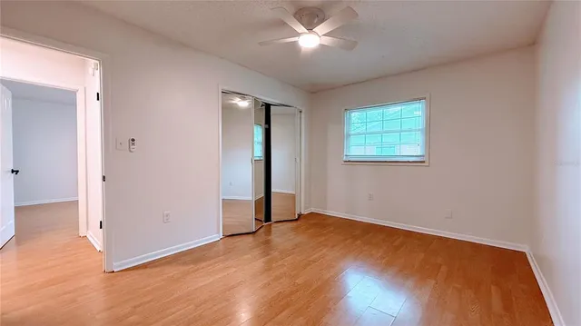 a view of an empty room with wooden floor and a window