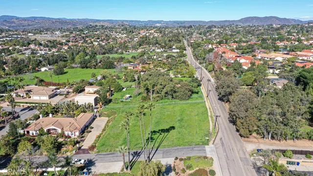 an aerial view of a residential houses with outdoor space and trees