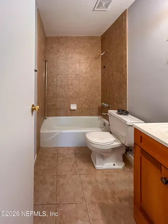 a view of an empty room with wooden floor and a bathroom