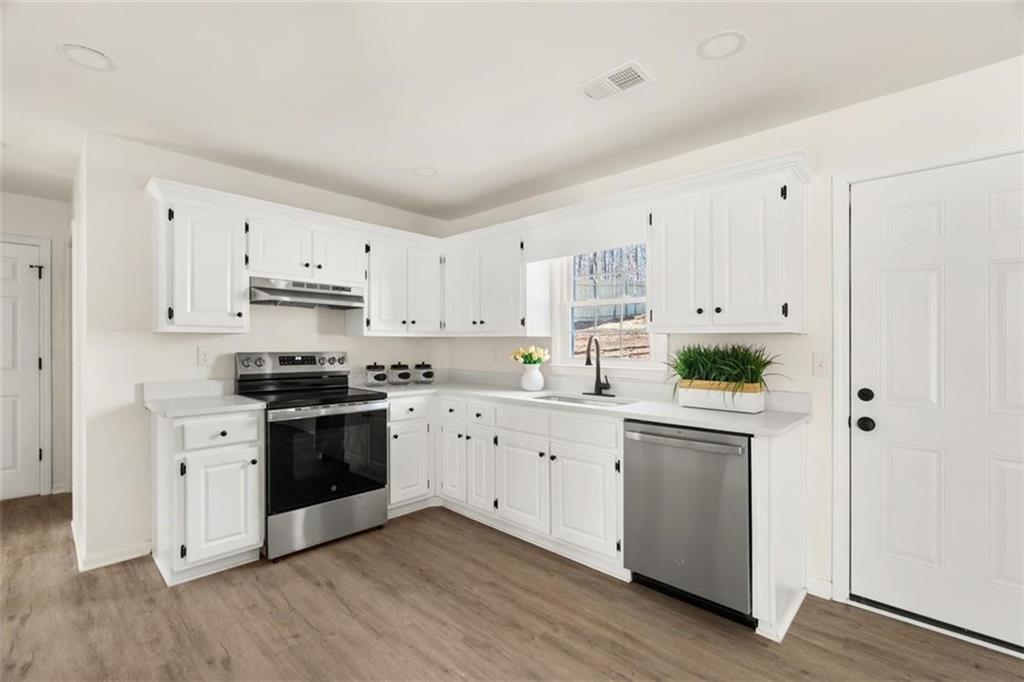 540 Riverside Road Sugar Hill, GA 30518 - Photo 6 of 25 a kitchen with stainless steel appliances granite countertop a stove a sink and white cabinets
