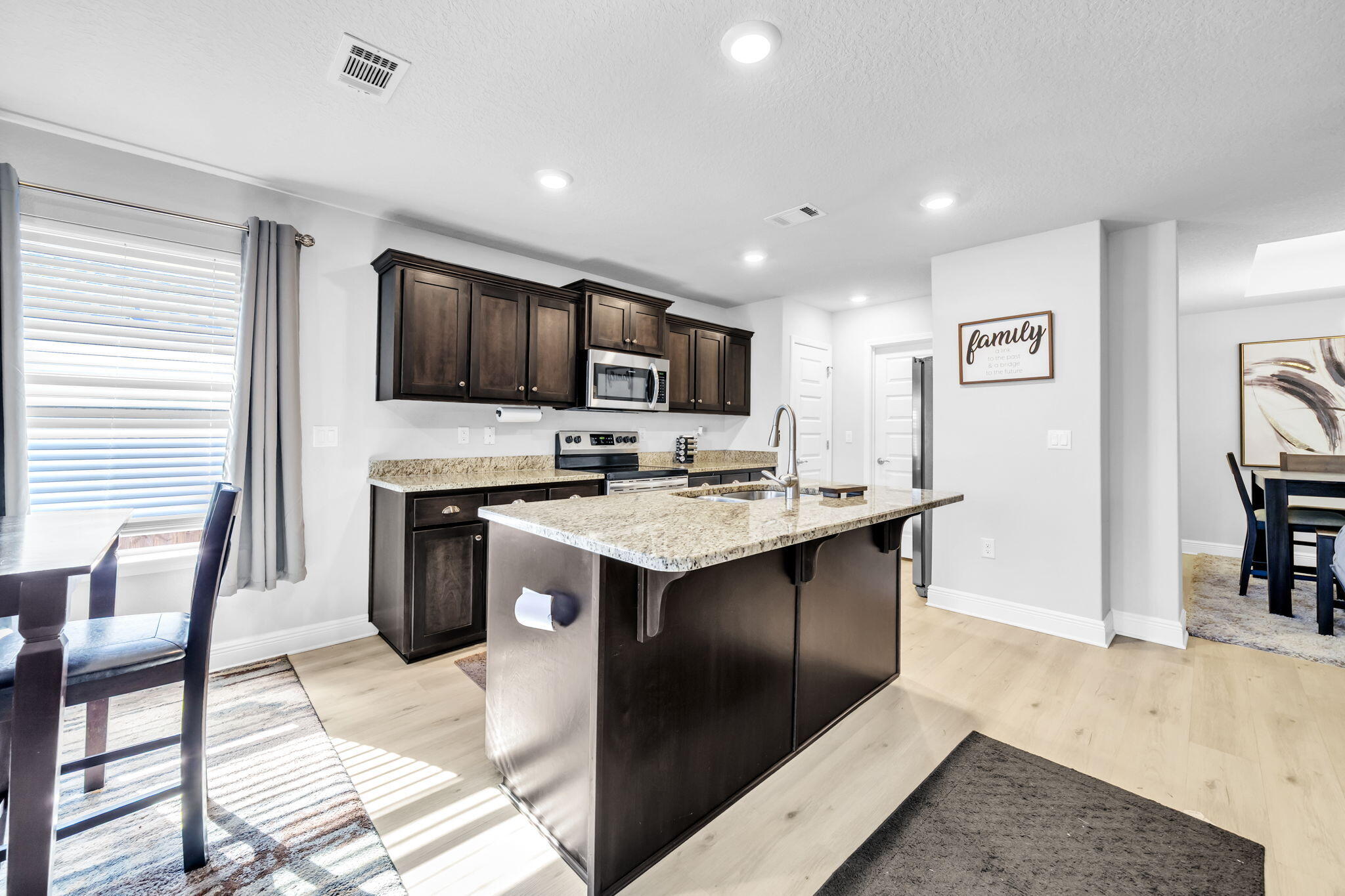 125 Ridgeway Circle Crestview, FL 32536 - Photo 24 of 41 a kitchen with stainless steel appliances kitchen island granite countertop a refrigerator a stove a sink a dining table and chairs with wooden floor