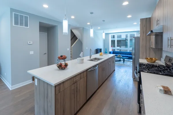 a living room with stainless steel appliances kitchen island a table chairs and wooden floor