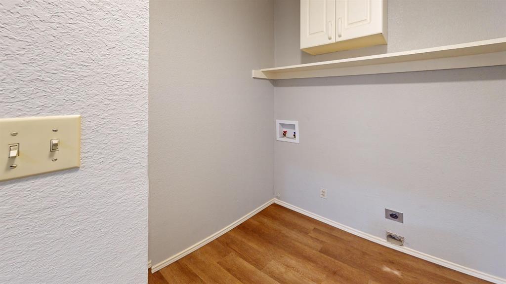 7913 Rice Drive Rowlett, TX 75088 - Photo 22 of 25 Utility area featuring wood-finish flooring, light-toned walls, built-in upper cabinetry, and a wall-mounted shelf