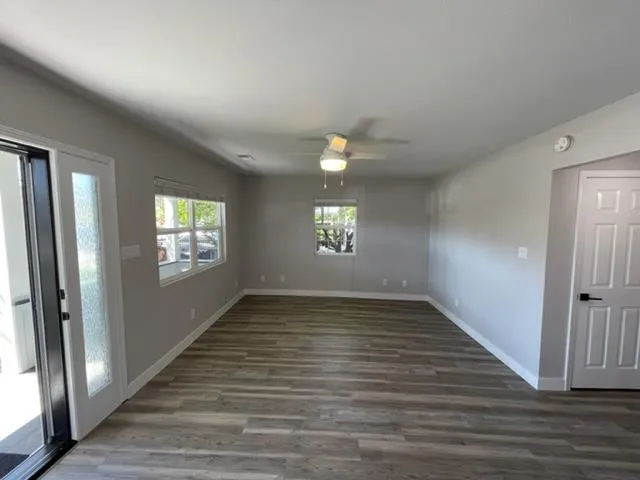 a view of an empty room with wooden floor and a window