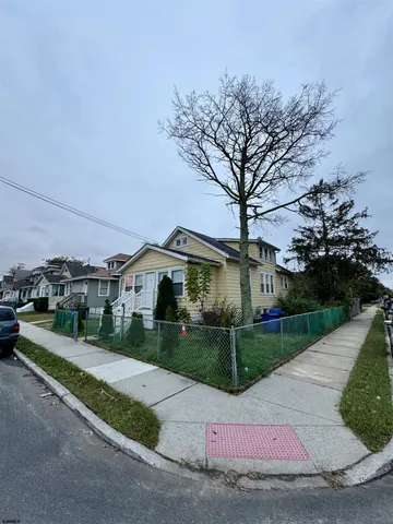 a view of a white house next to a yard and road