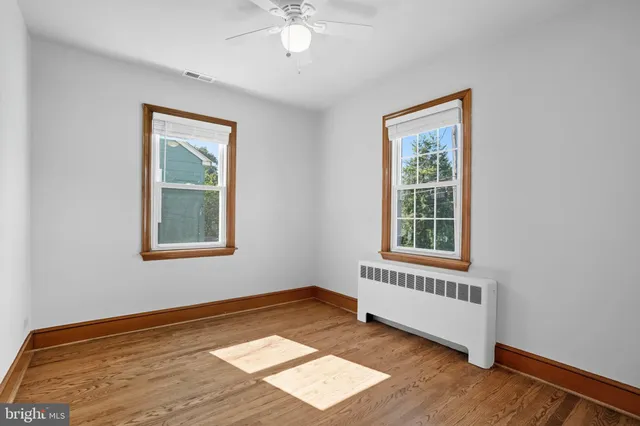 an empty room with wooden floor and a ceiling fan