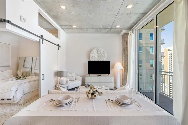 a living room with furniture a flat screen tv and a floor to ceiling window