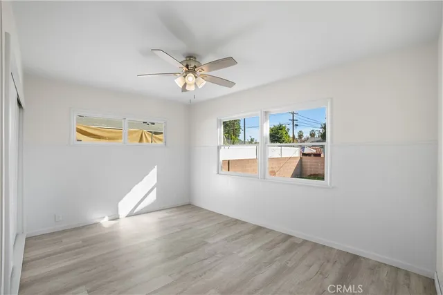 a view of empty room with wooden floor and fan