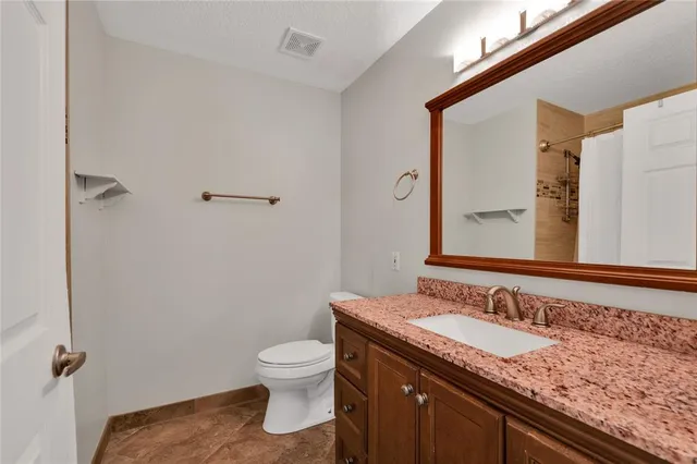 a bathroom with a granite countertop sink toilet and shower
