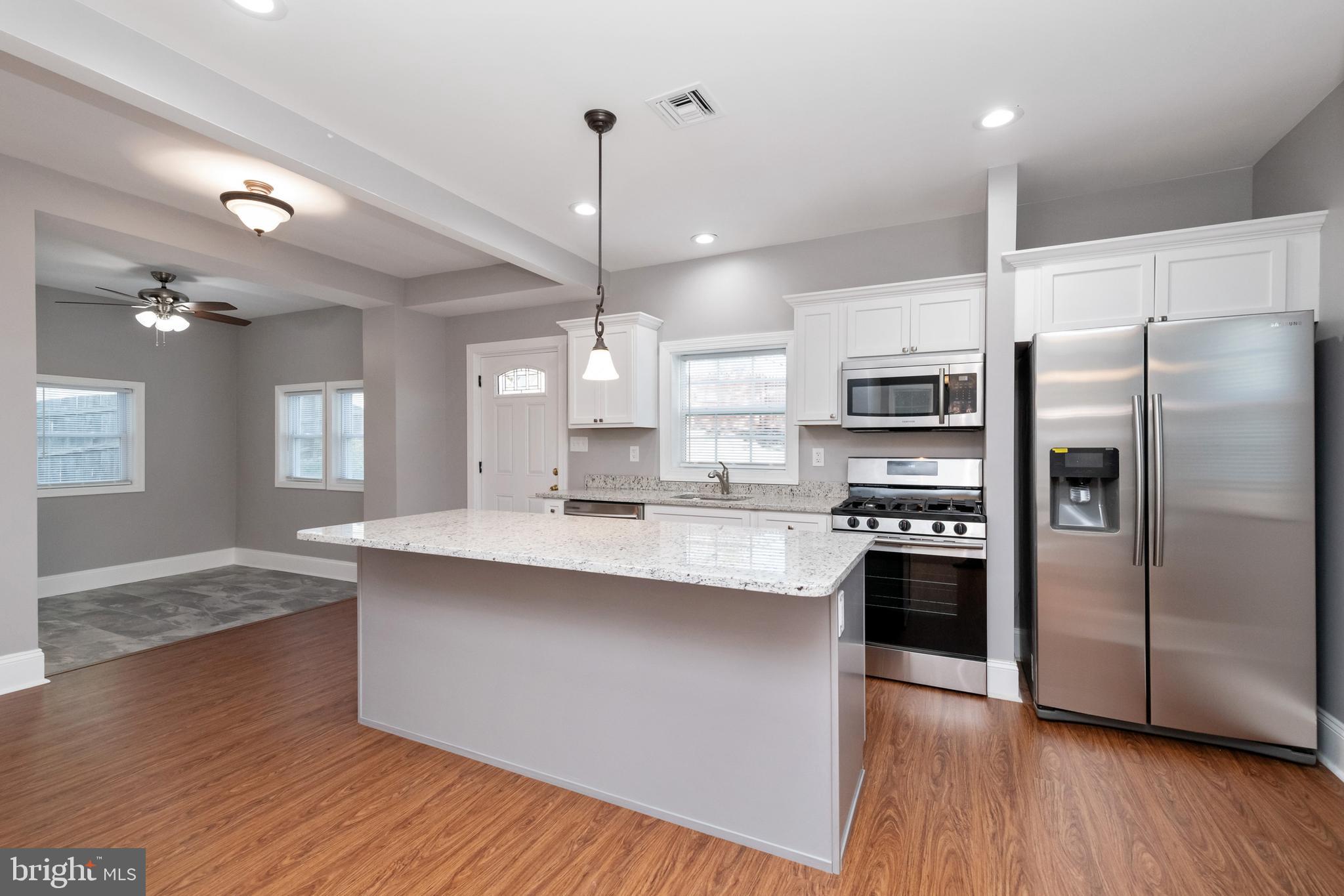 2505 Hammonds Ferry Road Baltimore, MD 21227 - Photo 14 of 36 a kitchen with stainless steel appliances granite countertop a sink a stove a refrigerator and island with wooden floor
