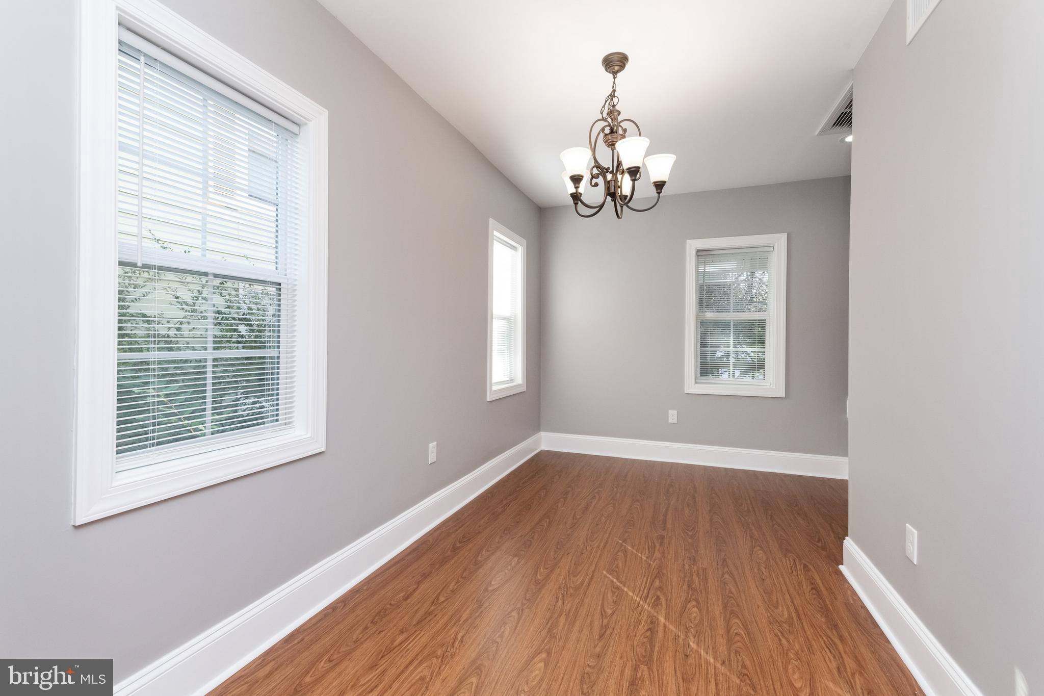 2505 Hammonds Ferry Road Baltimore, MD 21227 - Photo 15 of 36 an empty room with wooden floor chandelier and windows