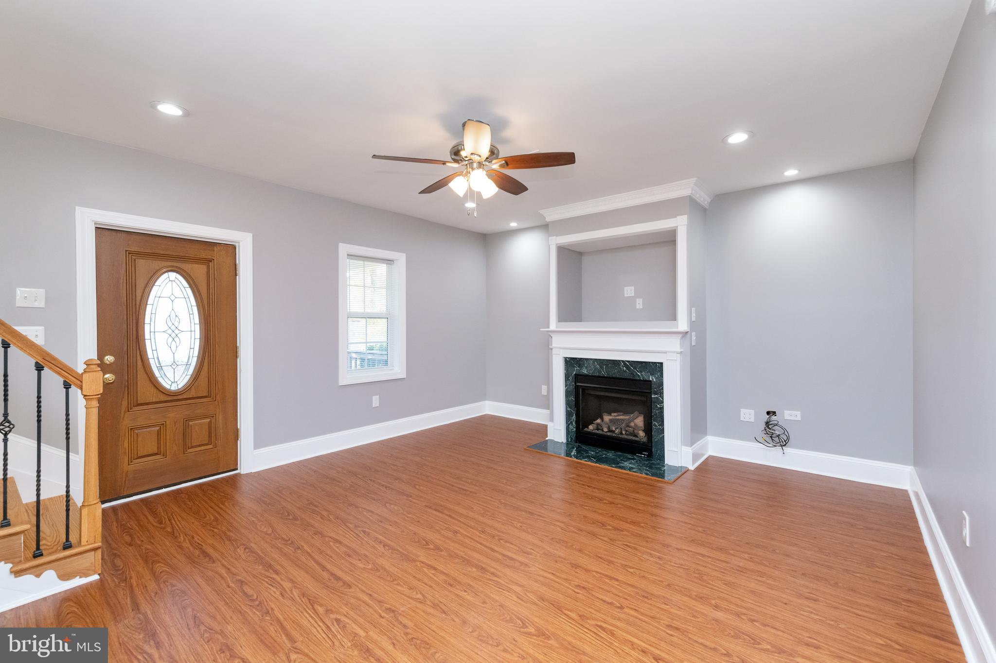 2505 Hammonds Ferry Road Baltimore, MD 21227 - Photo 7 of 36 a view of a livingroom with a fireplace wooden floor and a chandelier fan
